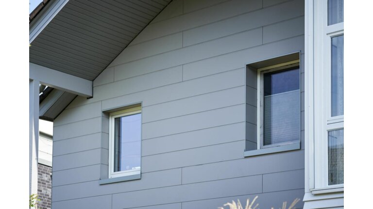 Schlichte graue Holzverkleidung mit klaren Linien an einem Haus, die für ein minimalistisches Erscheinungsbild sorgt.